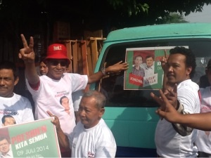 Ketua tim pemenangan Jokowi-JK Sidoarjo, Tito Pradopo (berkacamata)  bersama sopir memasang stiker Jokowi-JK