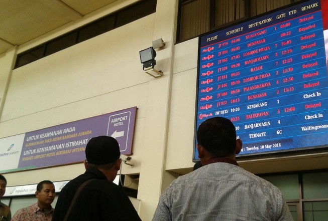 Penumpang Lion Air melihat jadwal keberangkatan di Bandara Juanda