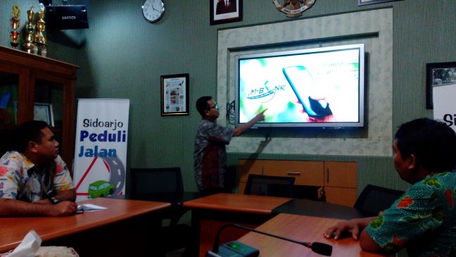 Kepala Dinas PU Bina Marga Sidoarjo Sigit Setiawan menunjukkan cara menggunakan  aplikasi M-bonk.